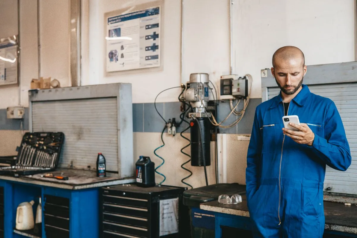 Técnico de macacão usando o celular em campo para abrir a ordem de serviço