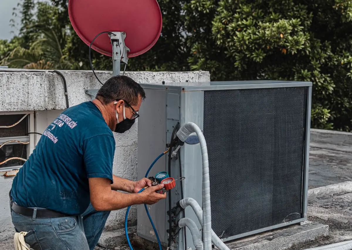 Técnico de refrigeração usando manifold e ferramentas no ar-condicionado