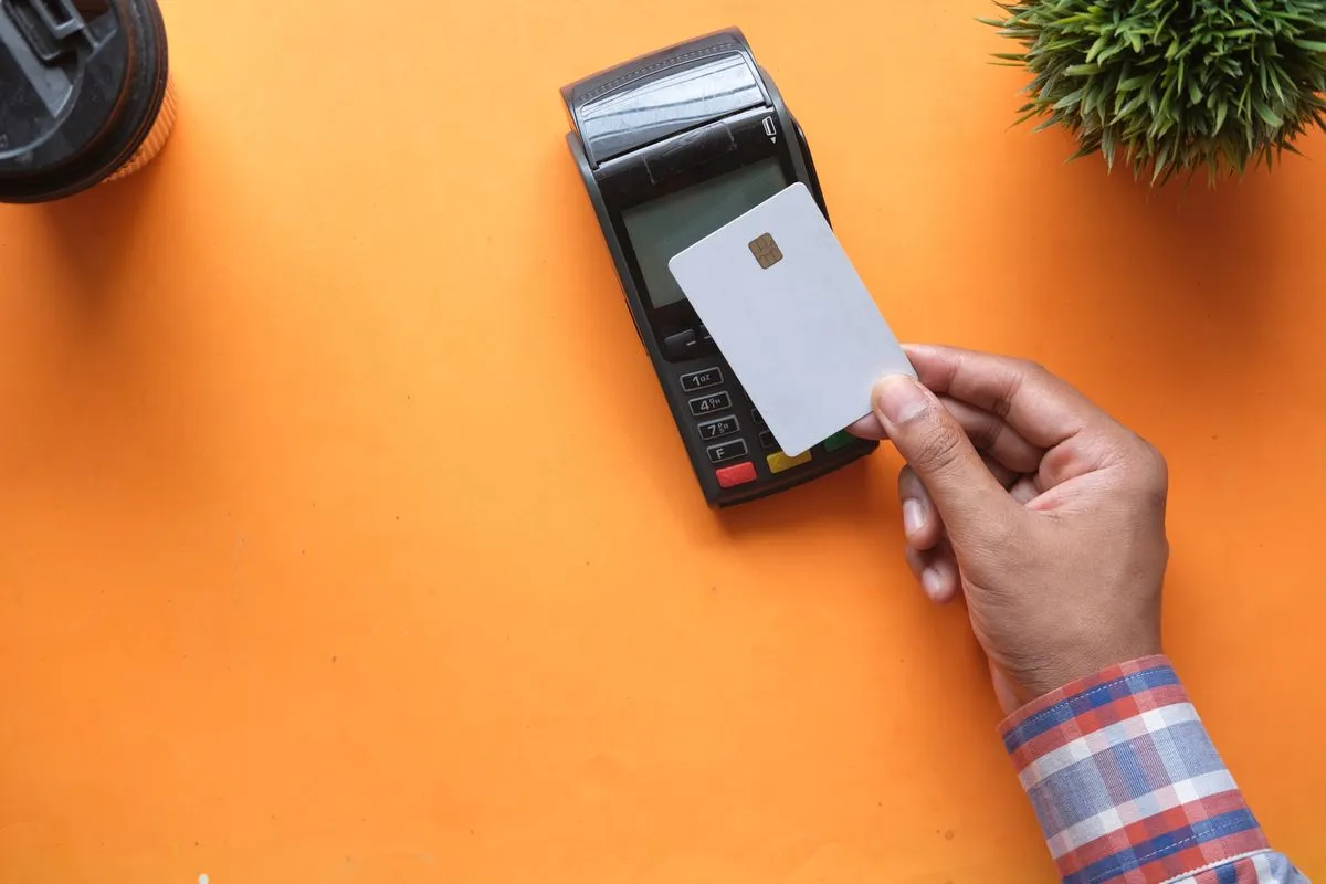 Pessoa fazendo pagamento por aproximação com cartão de crédito em uma maquininha