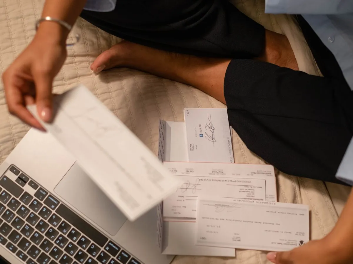 Pessoa organizando documentos e usando um notebook na mesa do escritório