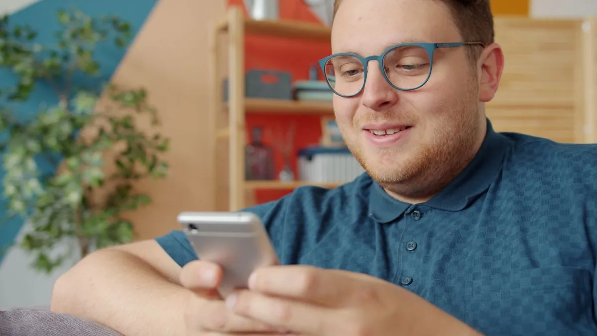 Cliente sorrindo acompanhando o atendimento pelo celular em casa