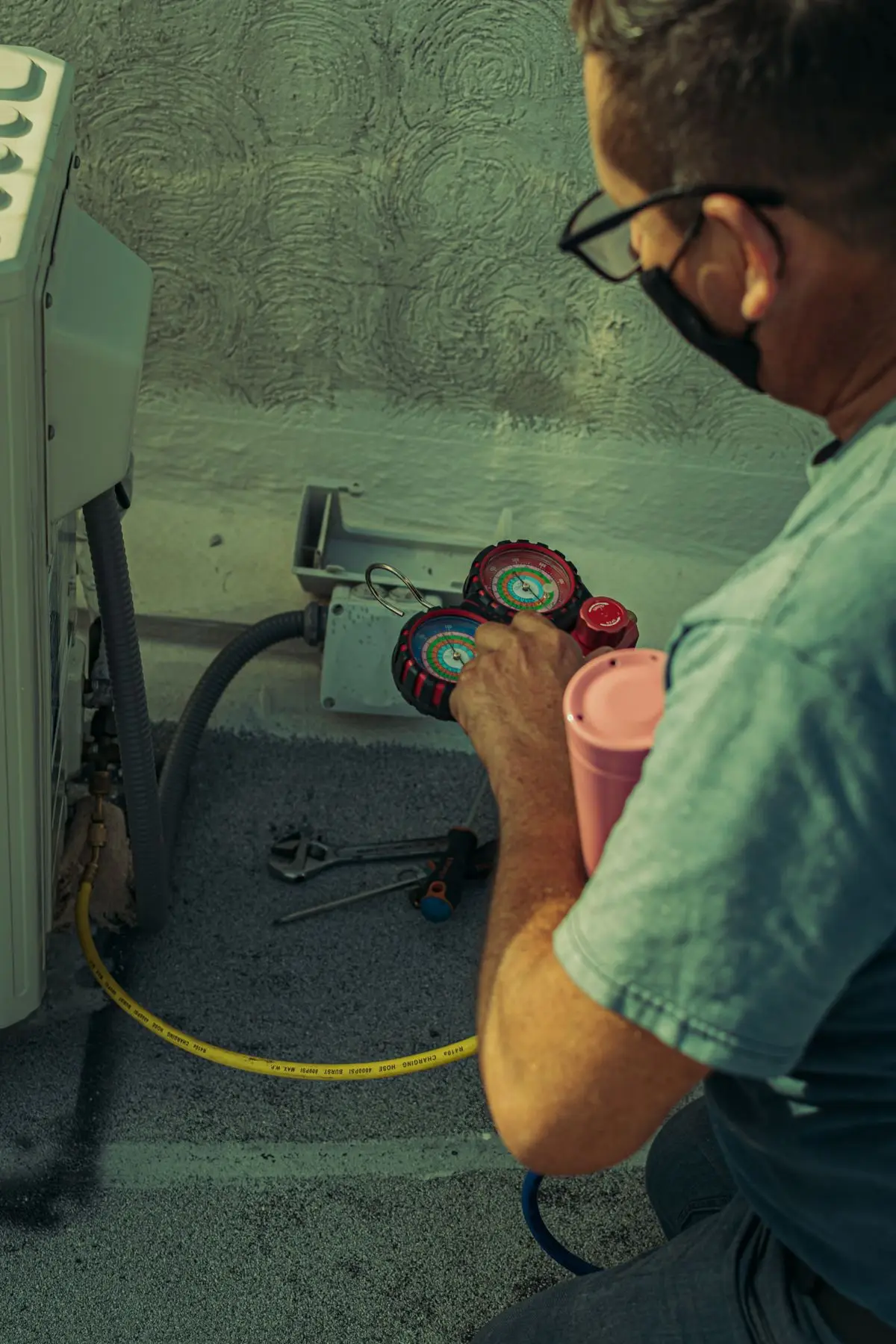 Técnico de refrigeração medindo gás com manômetros na condensadora do ar-condicionado