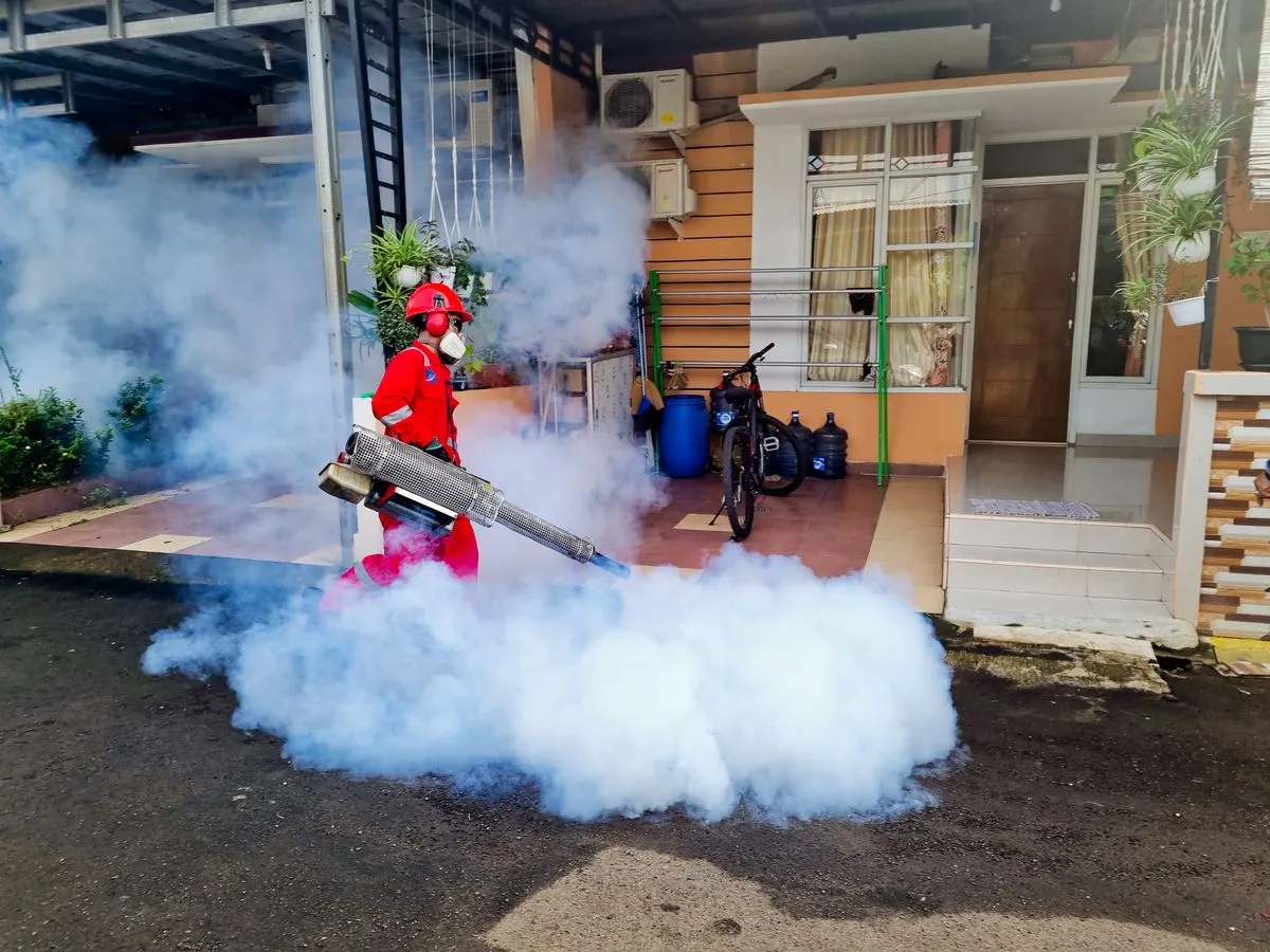 Técnico de controle de pragas aplicando termonebulização com máquina de fumaça