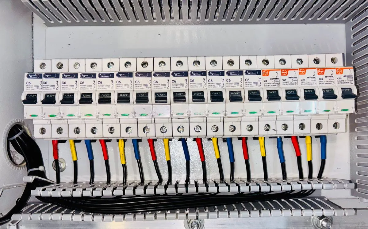Quadro de distribuição elétrica organizado, com disjuntores e fiação codificada por cores