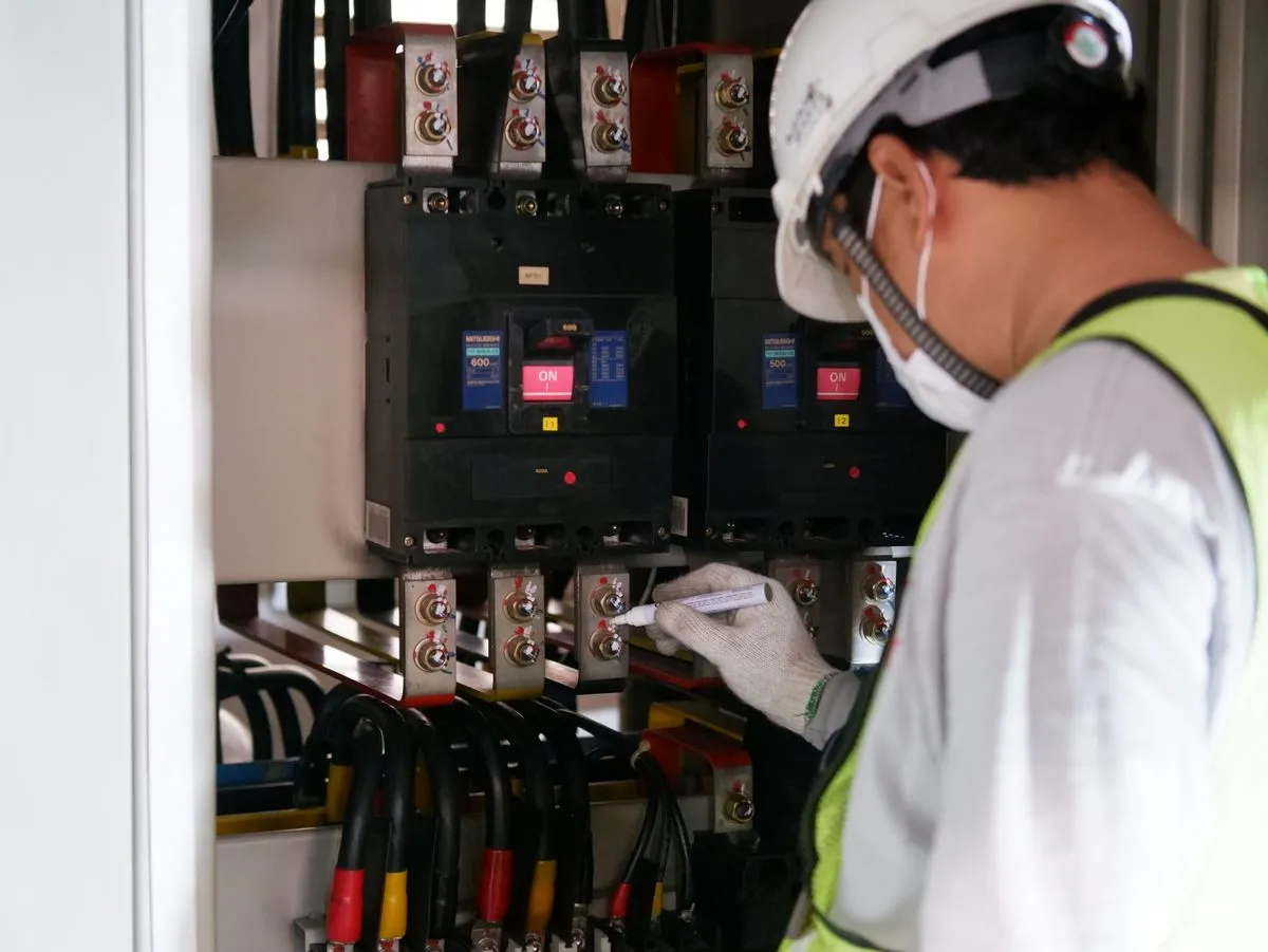 Técnico com EPI fazendo manutenção em painéis elétricos em ambiente industrial