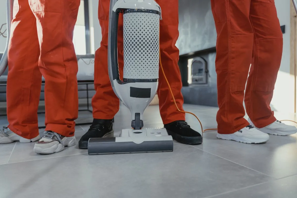 Equipe de limpeza profissional uniformizada aspirando o piso de um ambiente comercial