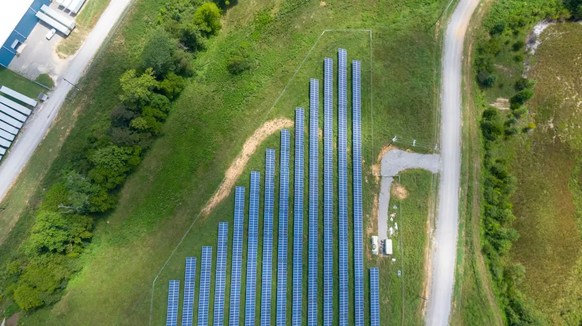 Vista aérea de uma usina fotovoltaica com fileiras de módulos solares em área rural