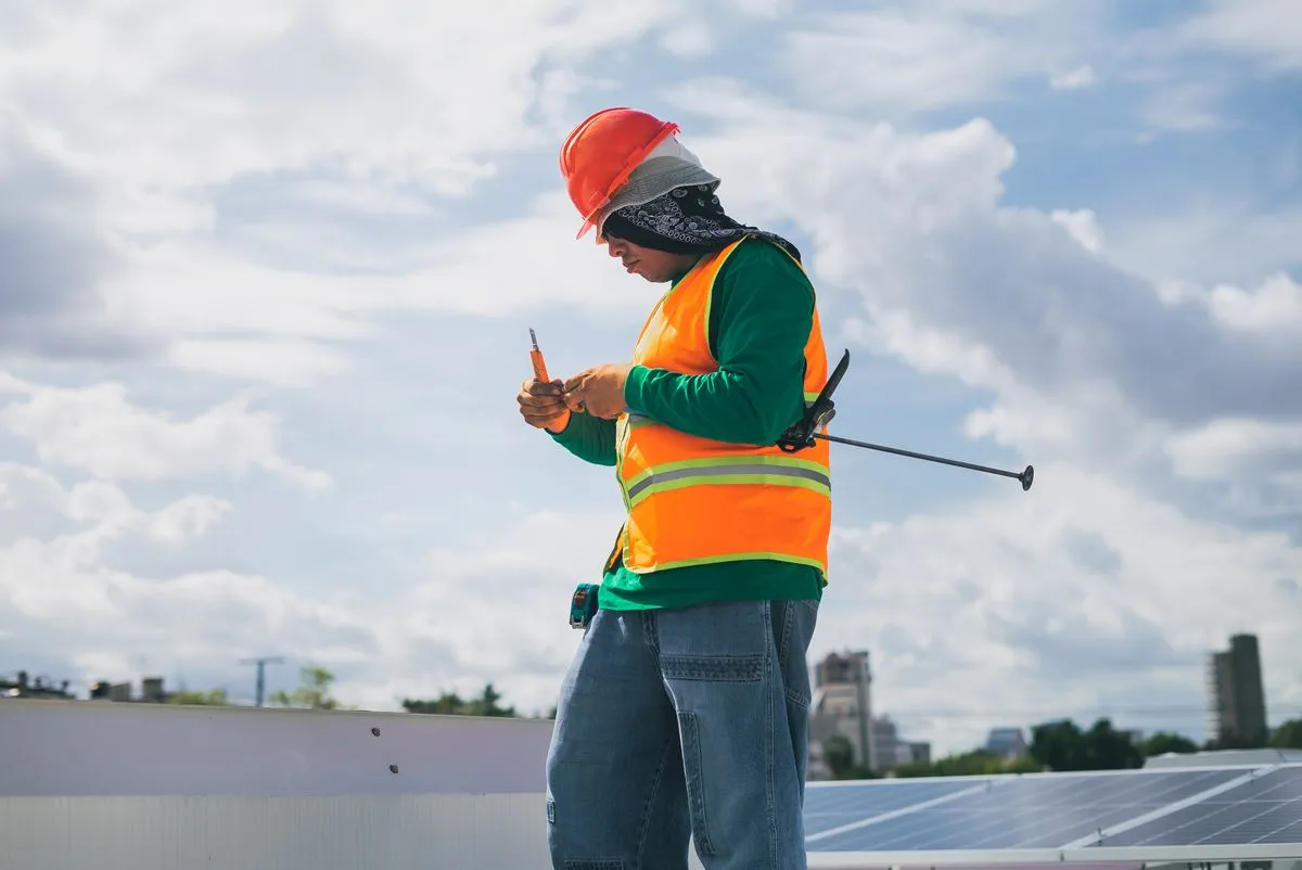 Técnico de energia solar com EPI trabalhando em módulos no telhado sob céu azul